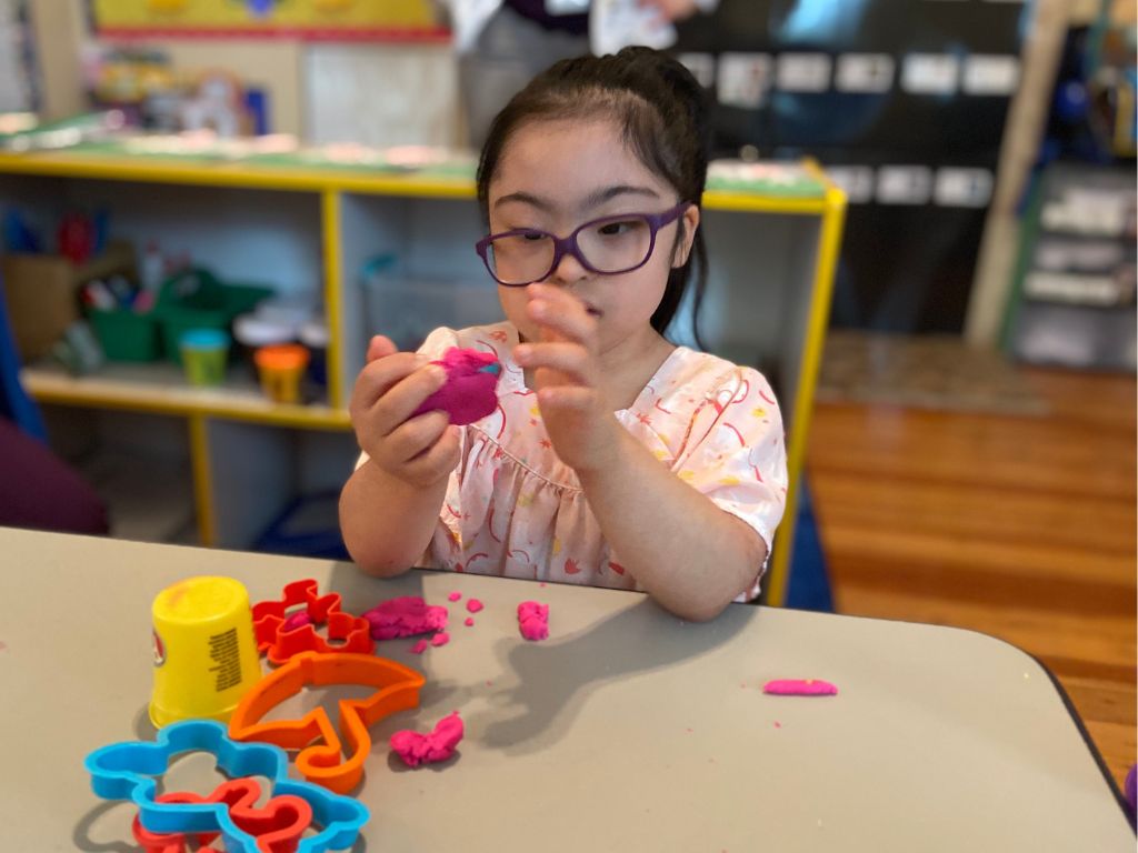 Little girl with Down syndrome plays with play dough