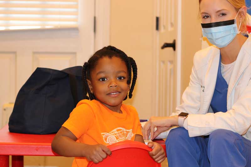 Un niño con necesidades especiales sentado con una enfermera sonríe a la cámara