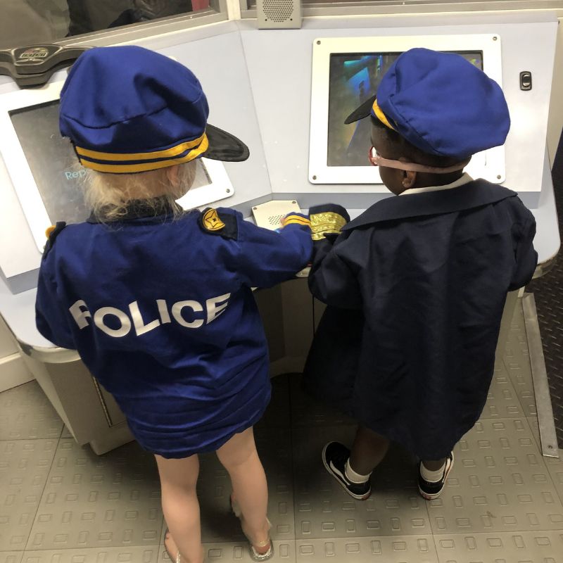 Two children playing police officers at video console.